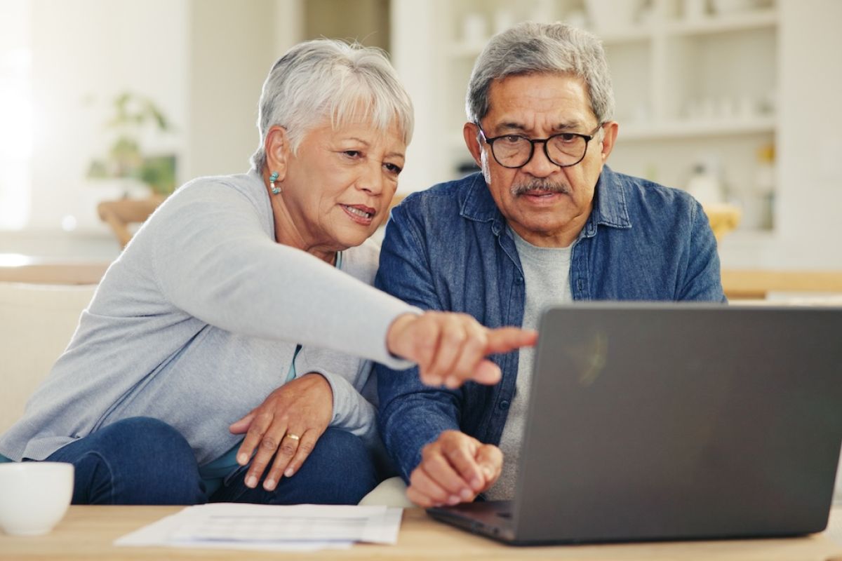 Older man and woman looking at a computer together to pay a bill