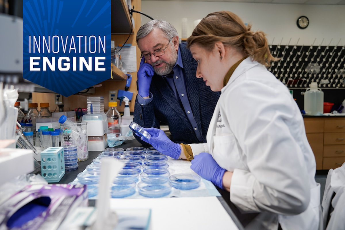 Dr. Andrei Gudkov in a lab with a colleague, with the Innovation Engine badge in the top left corner.