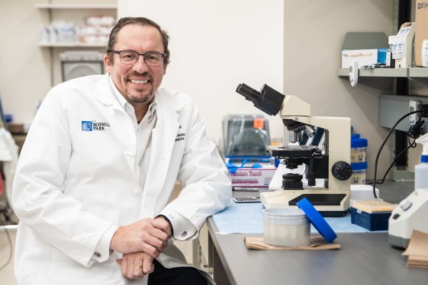 Scientist sitting at a bench with a microscope