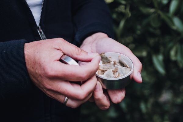 Person holding a tin of chewing tobacco in their hand 