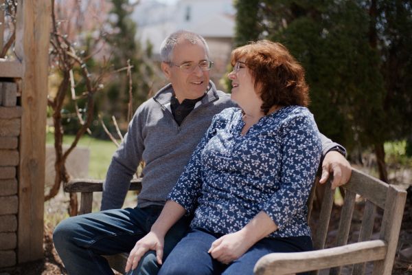 Tim, a Roswell Park cancer patient, sits smiling with his wife, Debbie, on a bench in their backyard.