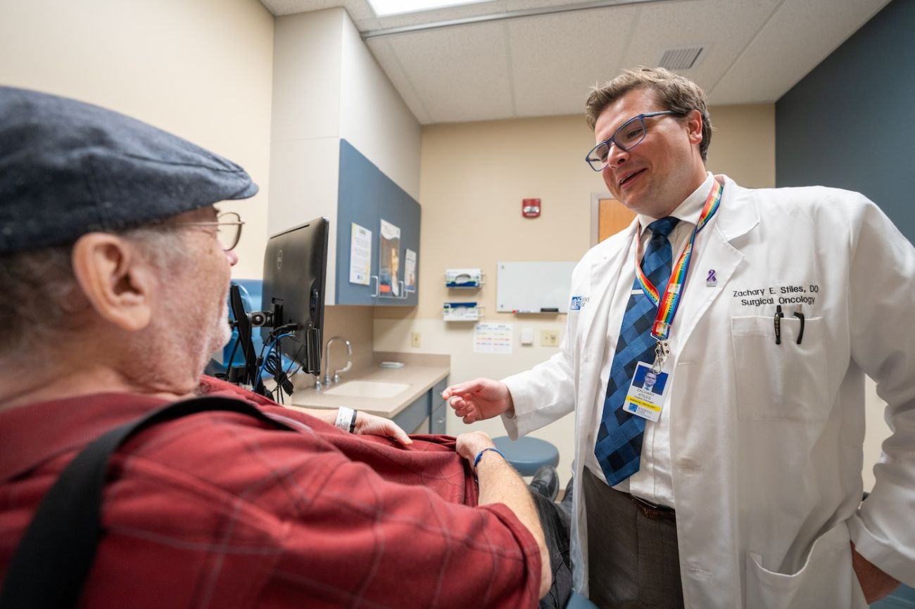 Dr. Zachary Stiles stands and smiles with a patient in clinic